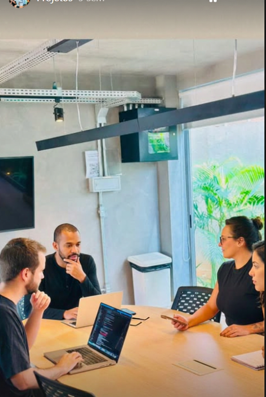 Equipe reunida em uma mesa de trabalho na OQI
